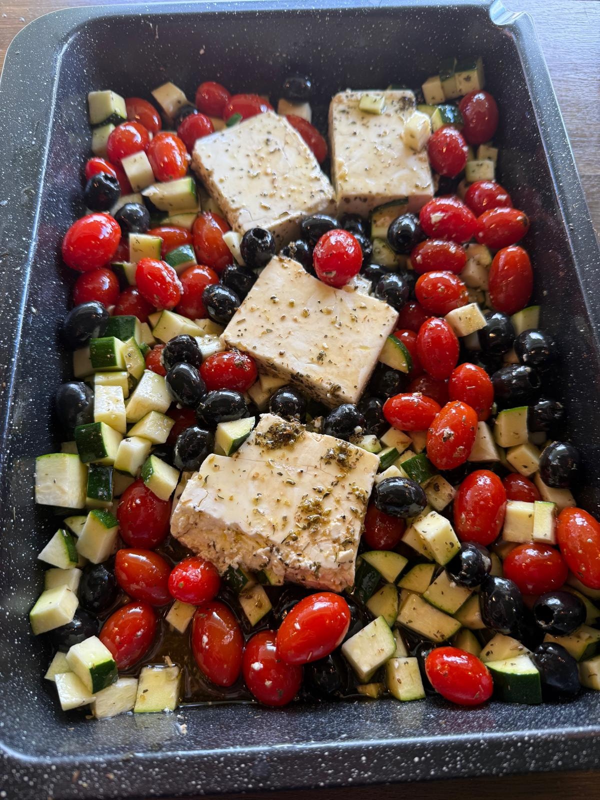 Feta, cherry tomatoes, courgette and olives prepared in a roasting tray